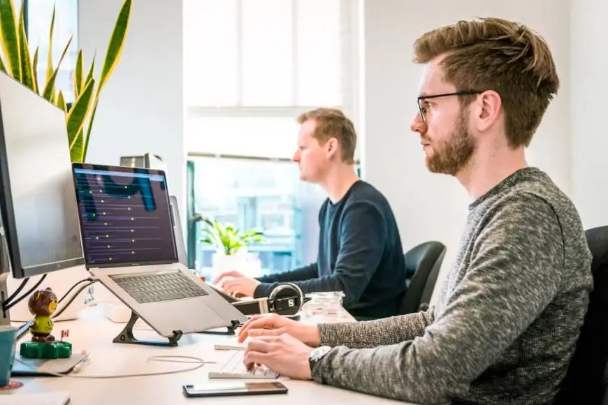  Two men in an office researching sales acceleration strategies on their computers