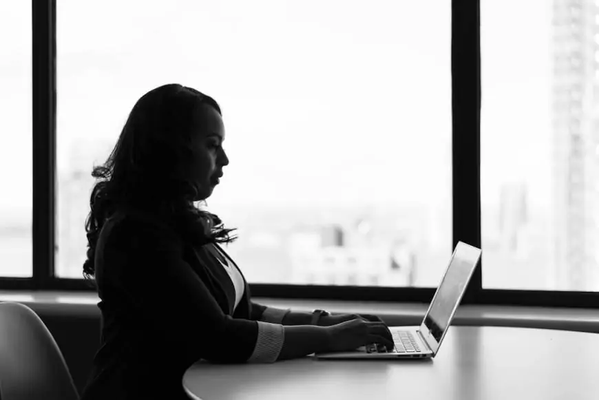 A professional woman seated at a desk in an office, working diligently on her laptop, understanding Intelligent Search and its evolution