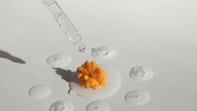 pipette with transparent essence and yellow flower on white surface